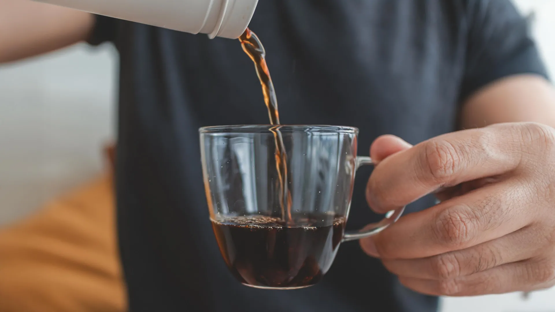 Pouring fresh coffee into a glass cup